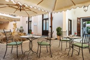 a patio with two tables and chairs with umbrellas at Donna Camilla Savelli - VRetreats in Rome