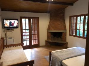 a living room with a fireplace and a tv at Pousada SerTão de Minas in Conceição da Ibitipoca