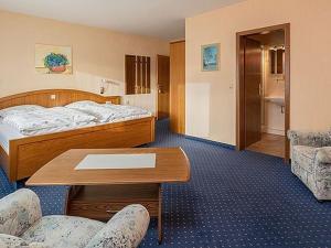 Una habitación de hotel con una cama, una mesa y sillas. en Landhaus Behle, en Willingen