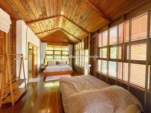 Un dormitorio con una cama en una habitación con ventanas. en วิลล่า ป่าเหมี้ยง Villa Pa Miang, en Ban Pa Miang