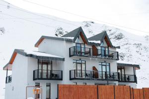 a white house with snow on the mountain at Kazbegi Estate in Kazbegi