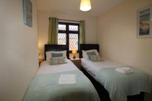 two twin beds in a room with a window at Wellington House in Codnor