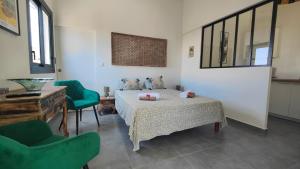 a bedroom with a bed and two green chairs at Ti kaz solei in Saint-Gilles les Bains