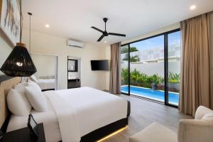 a bedroom with a white bed and a pool at The Grand Daha Luxury Villas in Seminyak