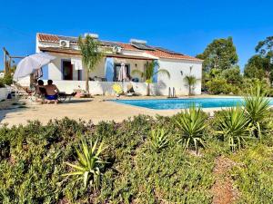a house with a swimming pool and two people sitting at Monte da Calcadinha in Ourique