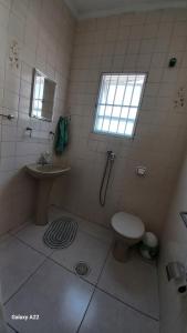 a bathroom with a toilet and a sink and a window at Oásis Flórida in Peruíbe +7 photos