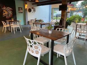 a restaurant with wooden tables and white chairs at BungaVilla Chalet in Port Dickson