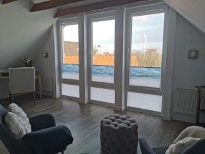 a living room with two large windows and a couch at Hotel Deichvoigt in Cuxhaven