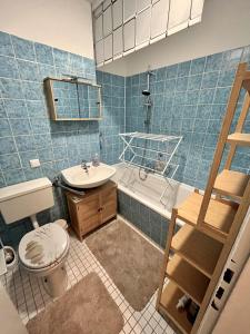 a blue tiled bathroom with a toilet and a sink at Kleine Oase am Mittellandkanal in Hannover