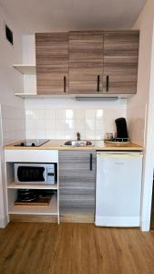 a kitchen with a white refrigerator and a sink at Appart Bréti Plage 1 avec parking - 50m de la plage in Bretignolles-sur-Mer