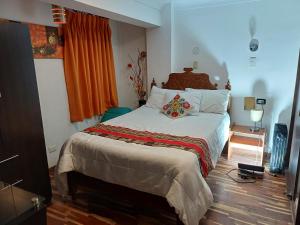 una camera da letto con un letto con lenzuola bianche e una tenda arancione di Hotel Cusco Museo a Cuzco
