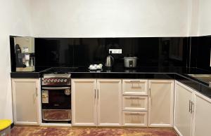 a kitchen with white cabinets and a black counter top at Oshi Villa Galle in Galle +54 photos