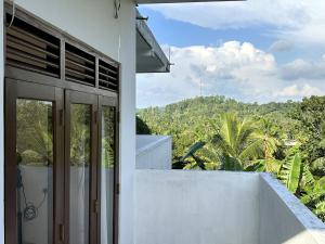 a white building with a balcony with a view of trees at Oshi Villa Galle in Galle
