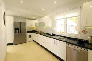 a kitchen with white cabinets and a stainless steel refrigerator at Casa de Suėños in Puerto del Carmen