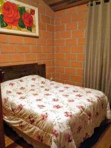 a bedroom with a bed with flowers on it at Chalé da Lu in Santo Antônio do Pinhal