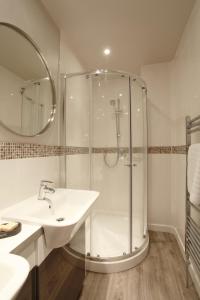 a white bathroom with a shower and a sink at Brindleys in Bath