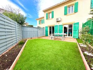a backyard with green grass and a fence at 10min de la mer Maison 6 personnes avec climatisation jardin in Fleury
