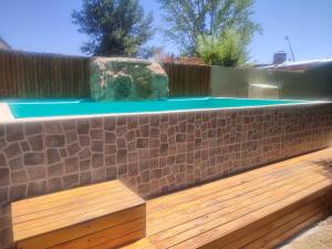 a swimming pool with a stone wall and a wooden deck at La Bohemia in Las Compuertas