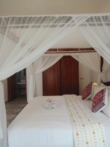 a bedroom with a white bed with a canopy at Home Villa in Lovina