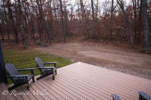 two chairs on a deck with a view of a field at Gorgeous Modern Chalet In The Woods in Wellston
