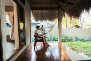 two people sitting on the porch of a house at Inigtan Lio Villas in El Nido