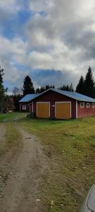 a red barn with a blue roof and a dirt road at Omakotitalo Haapavesi Mieluskylä in Ollilanperä +7 photos