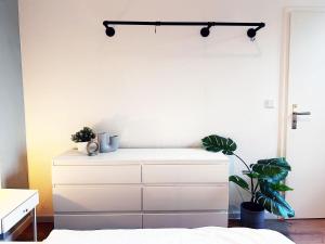 a white dresser in a bedroom with plants on it at 60qm Apartment in Viersen zentral gelegen mit hohen Decken - BEUYS Apartments - Viersen in Viersen