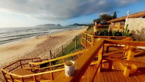 a cup of coffee sitting on a deck next to the beach at Mar&sol 80 metros da Praia Charme e Conforto in Florianópolis