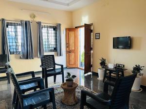a living room with chairs and a flat screen tv at Happy Hampi Home in Hospet +20 photos