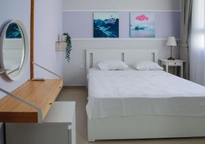 - une chambre blanche avec un lit blanc et un miroir dans l'établissement One Bedroom Apartment in Caesar Resort & SPA, Long Beach, à Perivolia tou Trikomou