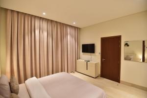 a bedroom with a bed and a television in it at Tulip Star Hawana in Salalah