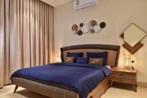 a bedroom with a large bed with blue sheets at Tulip Star Hawana in Salalah