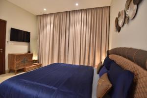 a bedroom with a blue bed and a television at Tulip Star Hawana in Salalah