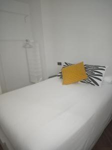 a white bed with a yellow and black pillow on it at Apartamento de dos habitaciones in Barbate