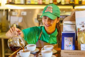 Eine Frau in einer Küche, die Kaffee in Tassen gießt. in der Unterkunft Hotel Campestre - CIUDADELA EL ARTESANO in Carolina del Principe