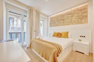 a bedroom with a white bed and a brick wall at Edificio Joya by Clabao in Pamplona
