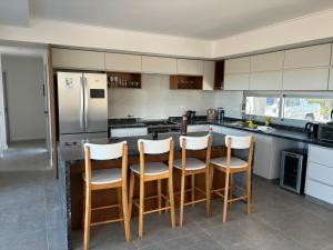 a kitchen with white cabinets and a bar with stools at La casa del lago in Chascomús