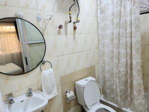 Un baño con inodoro, lavabo y espejo. en Home 11, en Lekki 5 fotos más