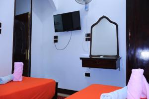 a room with two beds and a mirror and a tv at BAYT ZAINA - Nubian hospitality house in Aswan