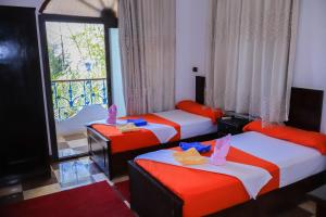 three beds in a room with a window at BAYT ZAINA - Nubian hospitality house in Aswan +139 photos