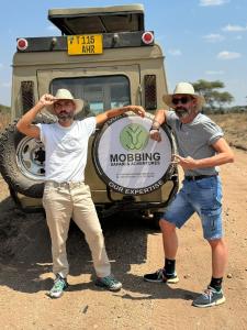 dos hombres están parados frente a un vehículo en Wildlife tour, en Arusha
