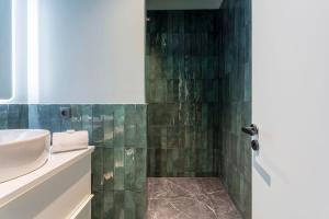een badkamer met een wastafel en een douche met groene tegels bij Suite St Antoine 4 travelers in Lyon