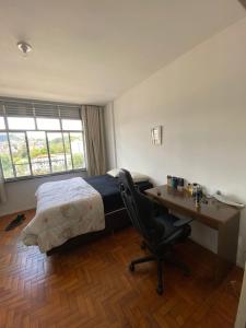 Un dormitorio con una cama, un escritorio y una silla. en Apartamento Centro de São Lourenço - com vista para o parque das águas, en São Lourenço