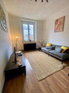 a living room with a couch and a table at Maison paisible, parking privé proche Micropolis in Besançon