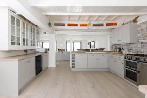 une grande cuisine blanche avec des armoires et des appareils blancs dans l'établissement Luxury Seafront Family Home - Indoor Pool, à Earnley 57 autres photos