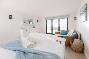 une chambre blanche avec un lit et une chaise dans l'établissement Luxury Seafront Family Home - Indoor Pool, à Earnley