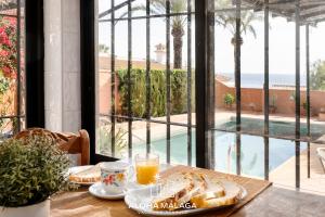 a table with a plate of bread and a glass of orange juice at LaCalma Village with private pool By AlohaMálaga in Málaga
