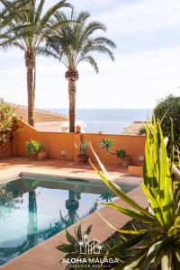 a pool with palm trees and the ocean in the background at LaCalma Village with private pool By AlohaMálaga in Málaga