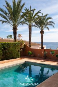 a swimming pool with palm trees and the ocean at LaCalma Village with private pool By AlohaMálaga in Málaga