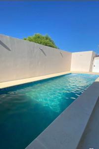 una piscina de agua azul junto a una pared en Santa Isabel Departamentos, en Valle María